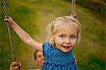 Portrait of a little girl playing on a swing in the back garden.