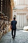 Young businessman makes a call as he strolls along a city street.