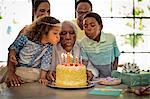 Senior man blowing out his birthday candles with his family.