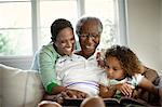 Grandparents reading with young granddaughter.