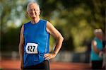 Portrait of a smiling senior man standing on a sports track.