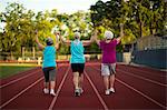 Senior women holding hands while walking on an athletic track.