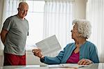 Elderly woman asks her worried husband about a bill they have received.