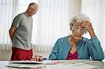 Anxious elderly couple worry about how they will pay all the bills they have received.