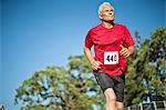 Active senior man running on a sports track.