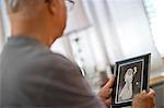 Senior man looking at an old wedding photo.