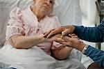 Senior man holding hands with his ailing wife.