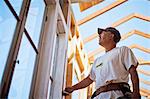 Middle aged builder working on the wooden framing of a building.