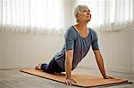 Mature woman practices peaceful yoga stretches in her home studio.