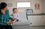 Mother sitting with her baby boy in a doctor's office.