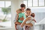 Loving parents tenderly cuddle their two young daughters.