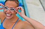 Portrait of a smiling young woman adjusting her swimming goggles.