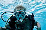 Young boy learning how to scuba dive in a pool.