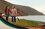 Mature couple walking towards their canoe.