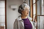 Portrait of a pensive senior woman looking out a window.