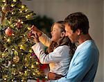 Happy father and daughter decorating a Christmas tree together.