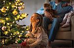 Young girl looking up at a decorated and illuminated Christmas tree.