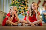 Two bored young girls waiting to open their Christmas presents.