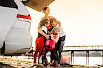 Three happy children hugging their smiling mother at the beach.