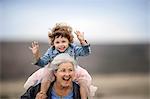 Mature woman carrying her granddaughter on her shoulders.