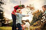 Grandmother raking leaves with grandsons.