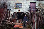 Blacksmith standing outside his workshop, looking at camera.
