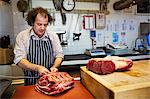 Butcher preparing a large piece of beef in a butcherer's shop.