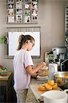 Family preparing breakfast in a kitchen, girl squeezing oranges.