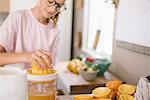 Family preparing breakfast in a kitchen, girl squeezing oranges.