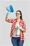 Pretty woman wearing gloves, using a cleaning spray and cleaning the house