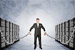 Businessman chained to iron boxes on grey background