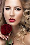 Beautiful blonde in a Hollywood manner with curls, red lips. Beauty face. Picture taken in the studio