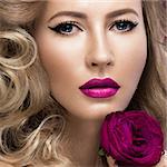 Beautiful blonde in a Hollywood manner with curls, pink lips. Beauty face. Picture taken in the studio