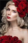 Beautiful blond girl in a dress and hat with roses, classic makeup, curls and red lips. Beauty face. Photos shot in studio