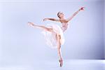 Young ballerina is dancing in a white studio full of light