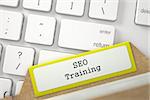 SEO Training Concept. Word on Yellow Folder Register of Card Index. Yellow Card File on Background of Modern Metallic Keyboard. Close Up View. Selective Focus. 3D Rendering.
