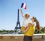 Having fun time near the world famous landmark in Paris. Seen from behind mother and child travellers rising flag in Paris, France