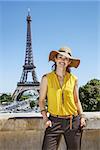 Having fun time near the world famous landmark in Paris. Portrait of smiling young woman in bright blouse in the front of Eiffel tower