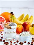 Healthy breakfast: cottage cheese with yogurt, fruits and nuts on white wooden background. Dieting, healthy lifestyle concept meal. Vertical with copyspace