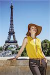 Portrait of relaxed young woman in bright blouse against Eiffel tower