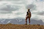 Man backpacker stands on mountains background. Success concept