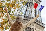 Autumn getaways in Paris. Seen from behind young elegant woman on embankment in Paris, France rising flag