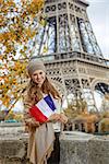 Autumn getaways in Paris. smiling young elegant woman on embankment in Paris, France with flag