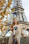 Autumn getaways in Paris. smiling young elegant woman on embankment near Eiffel tower in Paris, France taking selfie using selfie stick