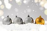 silver and golden decorative christmas balls on snow against grey festive background