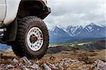 Big car wheel is standing on the rocks on mountain backdrop. Altay mountains, Siberia, Russia