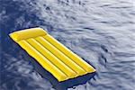 Yellow inflatable pool mattress floating on wavy water