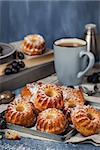 Fresh homemade delicious mini bundt cakes (muffins) and cup of coffee on background