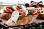 Italian bruschetta with tomatoes, mozzarella cheese and herbs on a wooden board