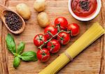 Fresh organic tomatoes with vegetables  and spagetti on wooden board. Potatoes,sause,pepper,basil,spagetti